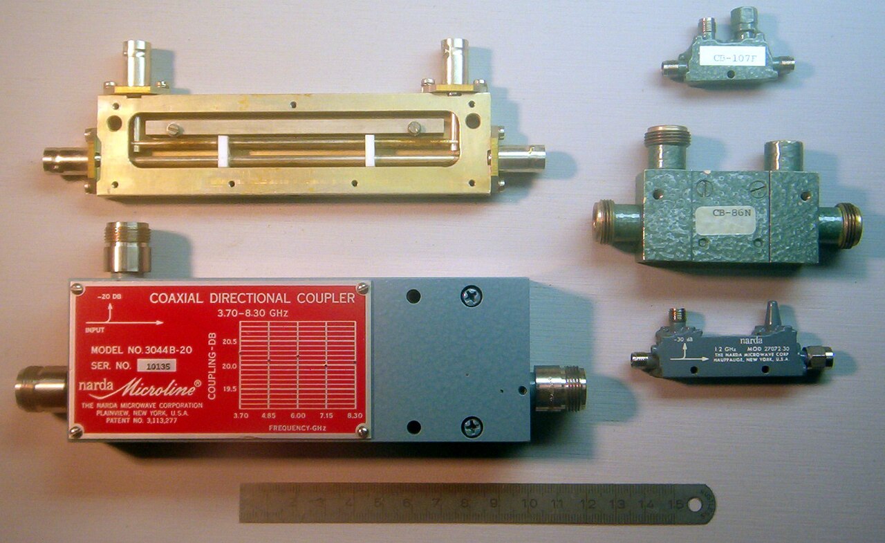 Figure 4 — Four coaxial directional couplers of different constructions, with a rule for scale. The Narda Microline 3044B-20 at lower left carries a printed coupling-versus-frequency calibration chart for 3.7…