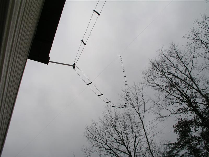 Figure 2 — A parallel-conductor transmission line strung from a house eave to a support well up in the trees — the same family of construction as the 300 Ω window line this build's matching stub is cut from, …