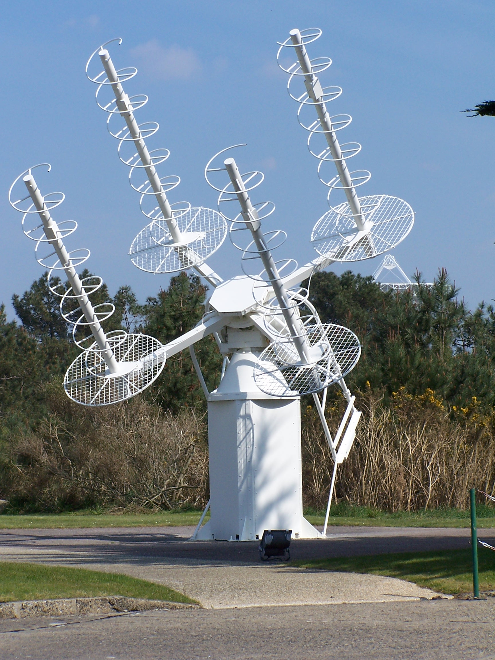 Figure 4 — Four axial-mode helices on a common az/el pedestal, each over its own mesh ground-plane disc. Photograph by Kingbastard, CC BY-SA 3.0, via Wikimedia Commons; the source identifies it as a satellite…