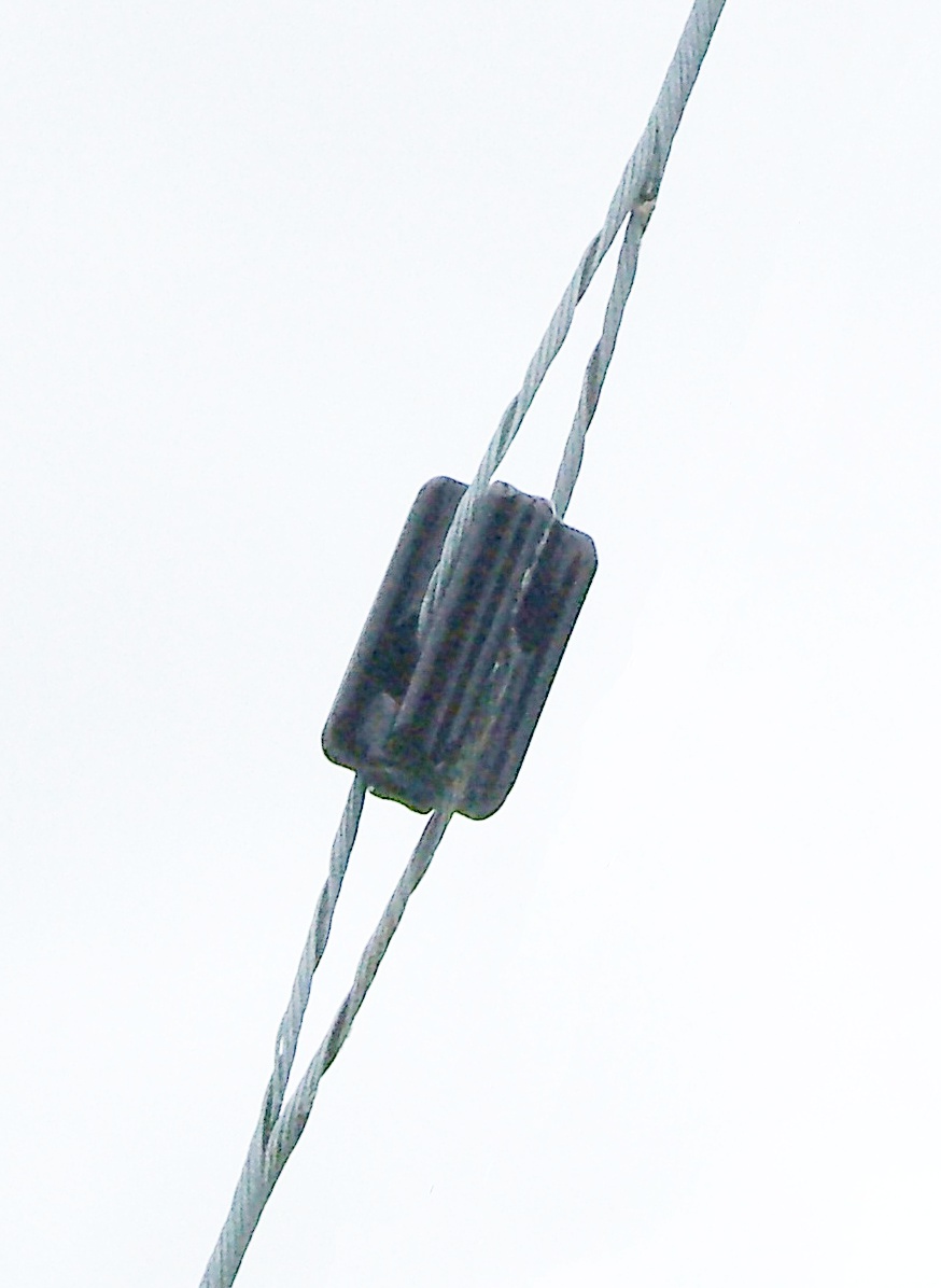 Figure 5 — A ceramic strain ("Johnny ball") end insulator of the type used to terminate each leg of a wire dipole — the antenna wire loops through one eye and the support rope through the other, so the insula…